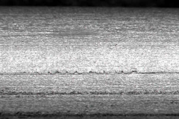 Visual of bright steel bars with surface defects, microstructure, and testing overlays