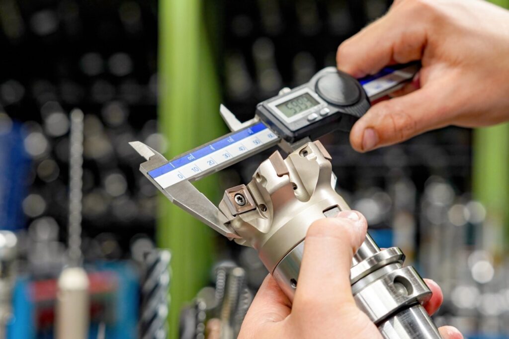 Bright steel bar being measured with digital micrometer for tolerance accuracy in industrial workshop